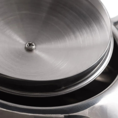 Close-up of a metal lid with a central screw on a reflective surface